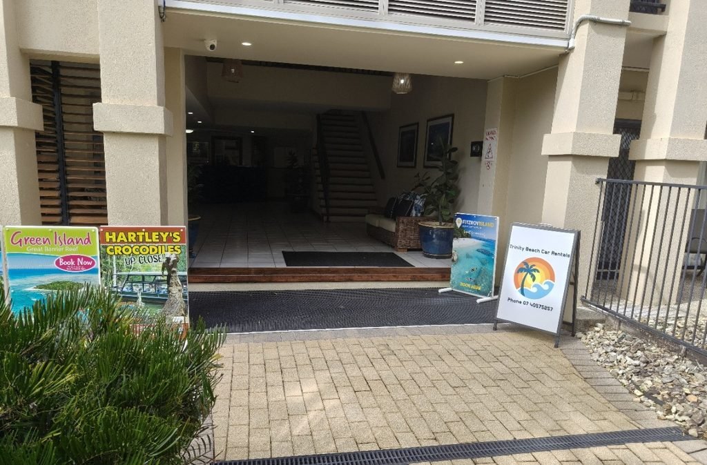 office pic - Entrance to a building with a lobby; promotional signs leaning against the wall advertising Green Island and Hartley's Crocodiles on the left, and rental signs on the right.